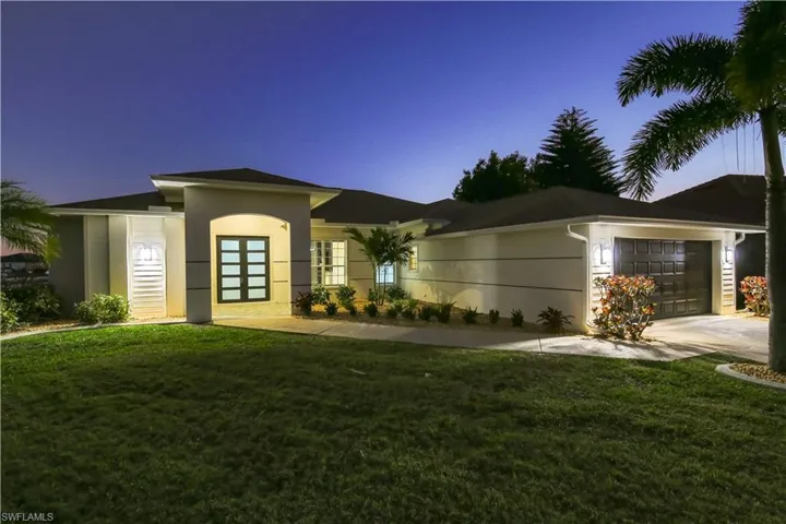 Prairie-style house with an attached garage, concrete driveway, a front lawn, and stucco siding
