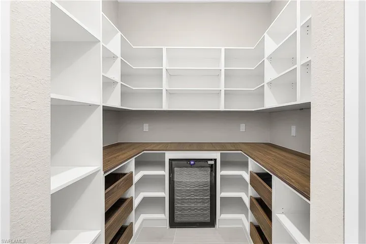 Butler's pantry featuring a wine cooler and storage helves and pull-out drawers