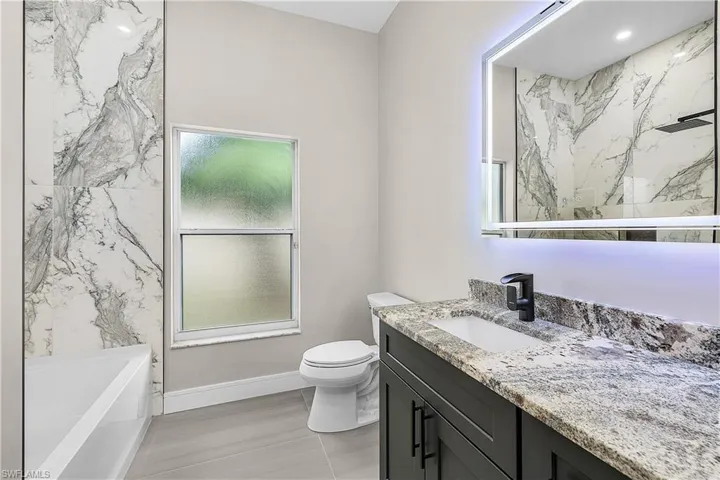 Full bathroom featuring vanity, a bathtub, and a marble finish shower