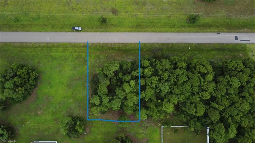 Property featuring a direct paved road frontage, mature trees, and a clear boundary outline