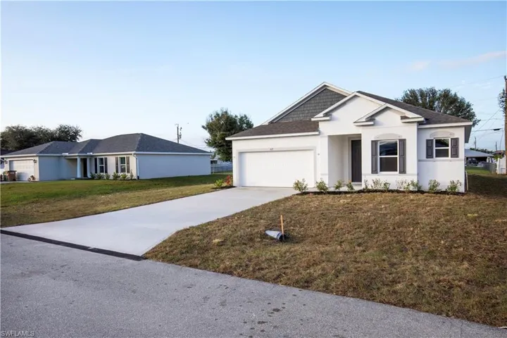 Single story home featuring driveway, a front yard, stucco siding, an attached garage, and a shingled roof
