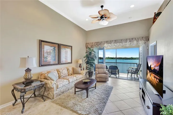 Living room featuring light tile patterned floors, ceiling fan, ornamental molding, a towering ceiling, and recessed lighting