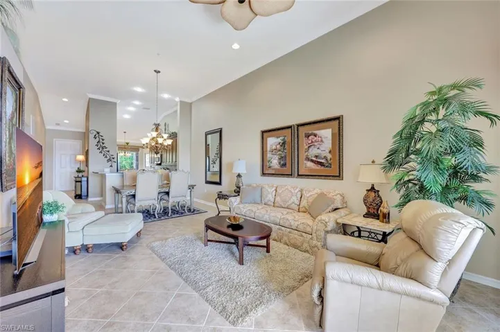 Living room with recessed lighting, light tile patterned flooring, a chandelier, ornamental molding, and ceiling fan