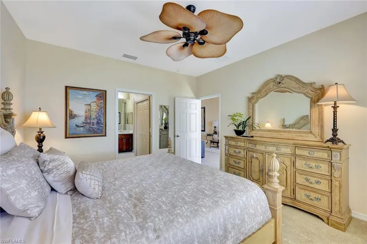 Bedroom with ceiling fan, light carpet, and connected bathroom