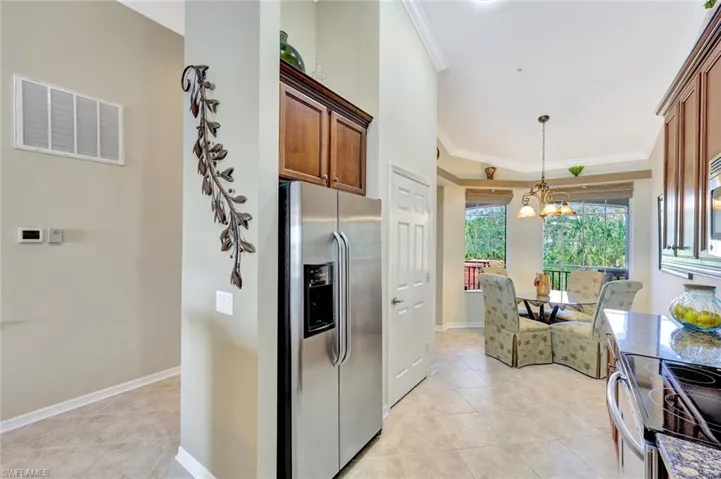 Kitchen featuring crown molding, stainless steel appliances, light tile patterned floors, decorative light fixtures, and a chandelier