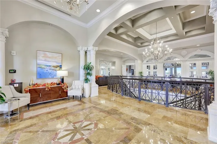 Hall with a chandelier, a towering ceiling, light marble finish floors, arched walkways, and coffered ceiling