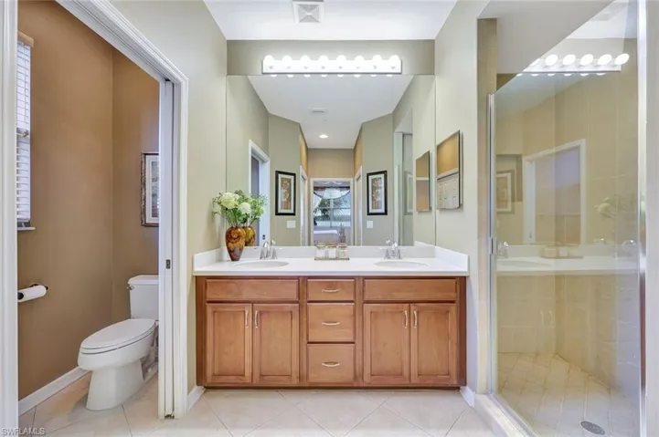 Full bath featuring light tile patterned floors, double vanity, and a shower stall