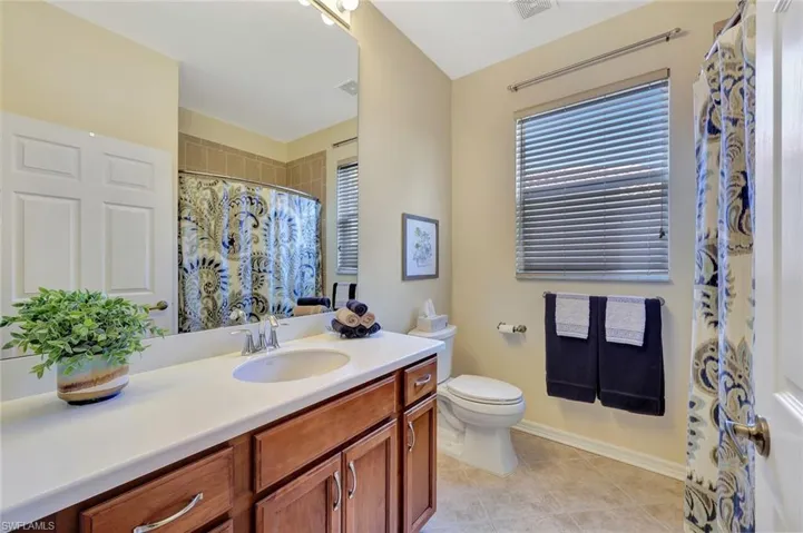Full bath featuring curtained shower, vanity, and light tile patterned floors