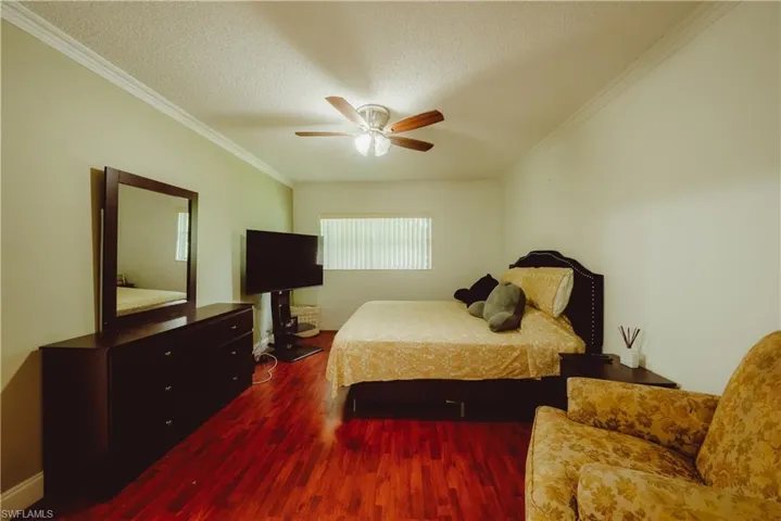 Bedroom with wood finished floors, ornamental molding, a textured ceiling, and ceiling fan