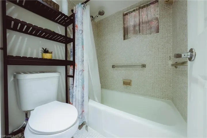 Bathroom featuring shower / bathtub combination with curtain and toilet