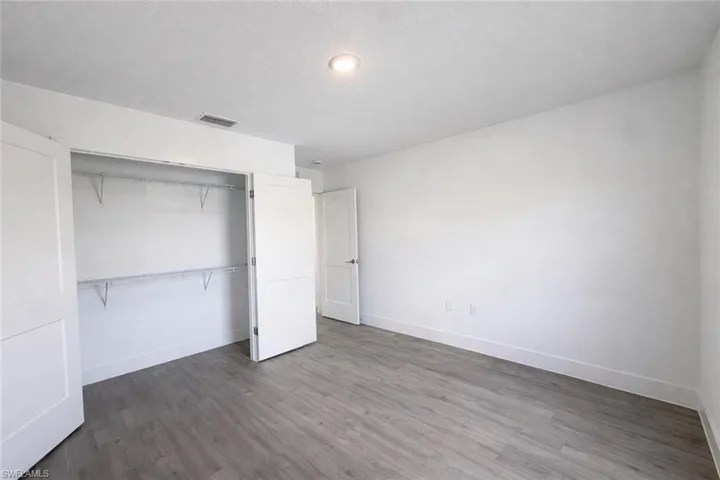 Unfurnished bedroom featuring dark wood-style flooring, a closet, and a textured ceiling