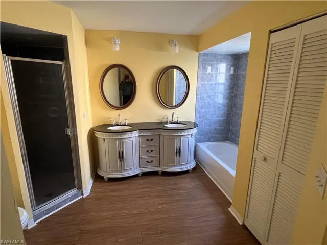 Primary Bathroom with dual sinks, walk in shower and tub.  Also shows 1 of the 2 walk in closets.