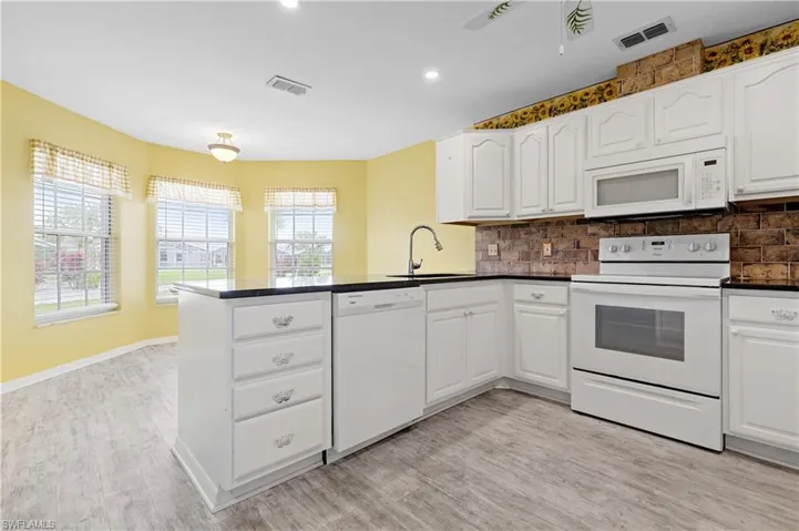 Overlooking back windows and dining area.  Granite countertops and white wood cabinates.