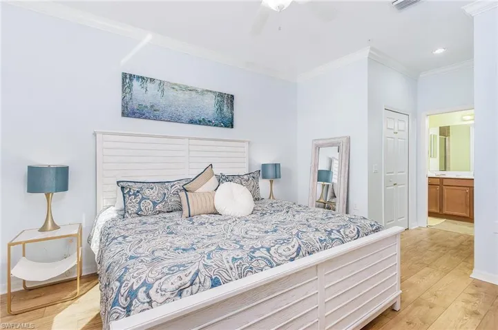 Bedroom with crown molding, light wood-style flooring, connected bathroom, a closet, and a ceiling fan