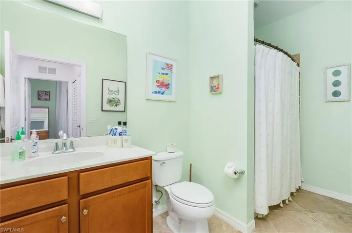 Bathroom featuring curtained shower, vanity, and light tile patterned flooring