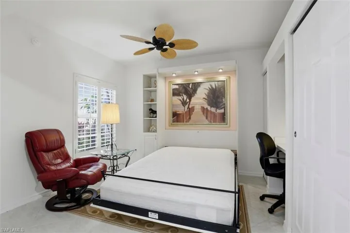Bedroom featuring ceiling fan, a desk, a closet, and light tile patterned flooring