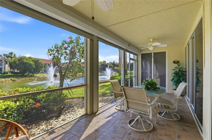 Sunroom / solarium with ceiling fan, outdoor dining area, a water view, and stone finish floors
