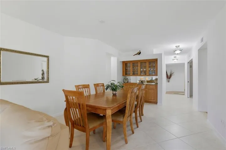 Dining room with light tile patterned floors and bar with sink