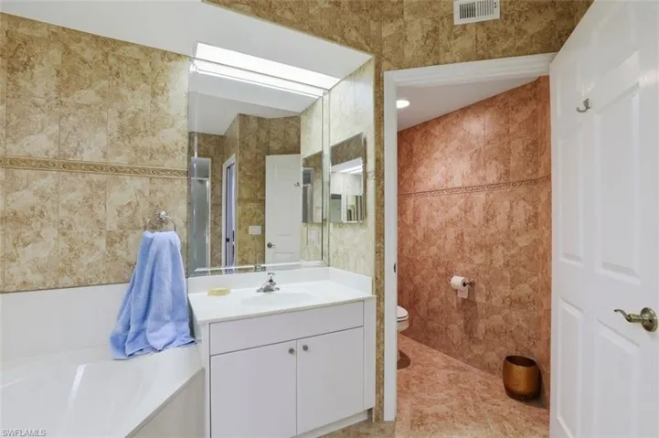 Full bath with tile walls, vanity, and a garden tub