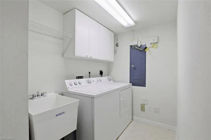 Laundry area featuring light floors, electric panel, cabinet space, and washer and dryer
