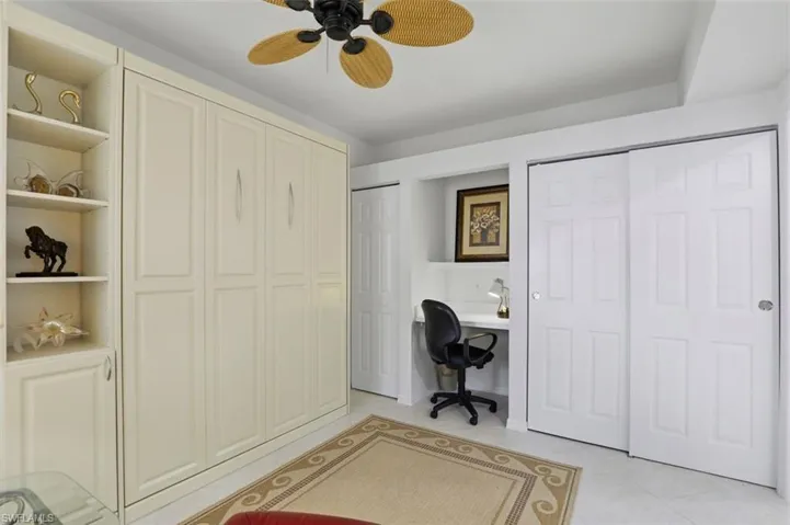 Office featuring ceiling fan, light tile patterned floors, and built in desk