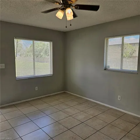Unfurnished room featuring a textured ceiling, a ceiling fan, and light tile patterned flooring