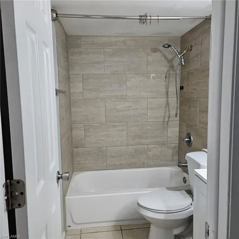 Bathroom with vanity, light tile patterned floors, and washtub / shower combination