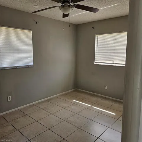 Spare room with a ceiling fan, a textured ceiling, and light tile patterned floors