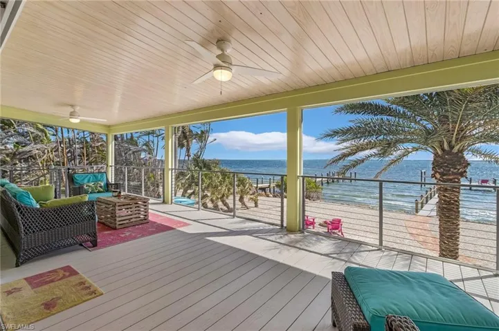 Deck featuring a view of the beach, outdoor lounge area, ceiling fan, and a water view