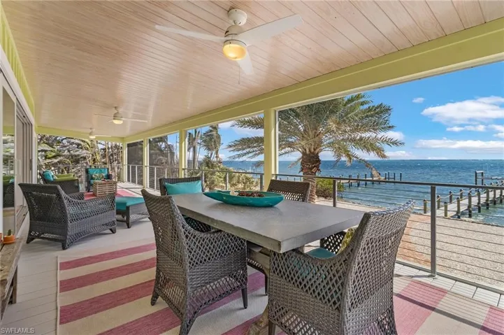 Sunroom / solarium featuring wood ceiling, plenty of natural light, ceiling fan, and a water view
