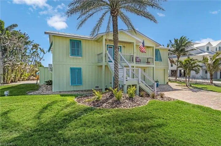 Rear view of property with a garage, a lawn, and covered porch