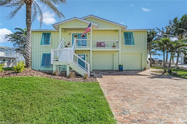 View of front of property featuring a garage, a balcony, covered porch, and a front lawn