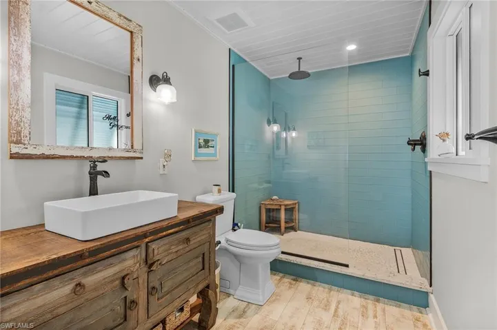 Bathroom featuring vanity, toilet, hardwood / wood-style floors, and a tile shower