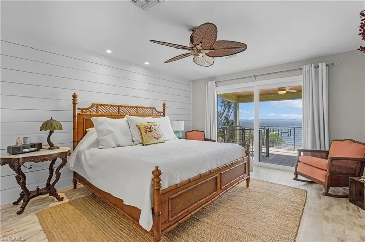 Bedroom with access to exterior, light hardwood / wood-style flooring, ceiling fan, and a water view