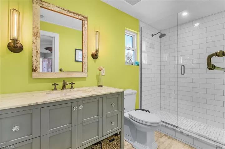 Bathroom featuring vanity, hardwood / wood-style floors, a shower with shower door, and toilet