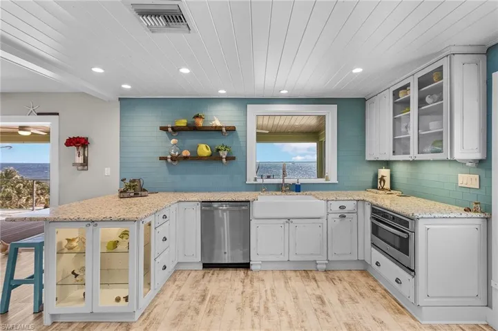 Kitchen featuring appliances with stainless steel finishes, light stone countertops, kitchen peninsula, and white cabinets