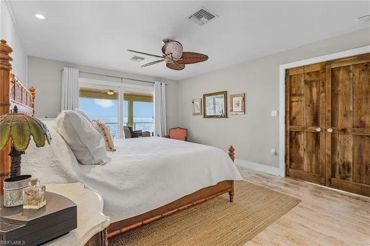 Bedroom with a water view, ceiling fan, and light hardwood / wood-style flooring