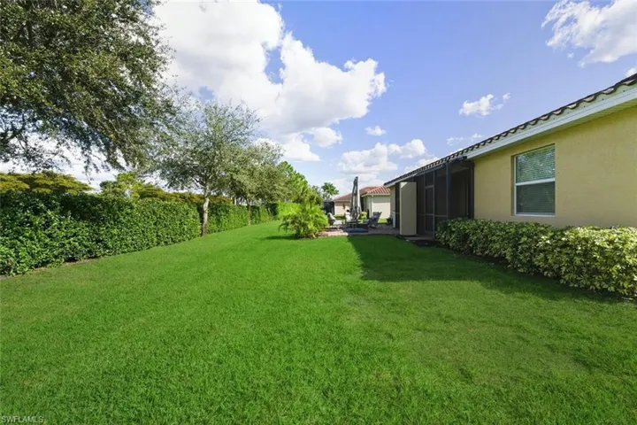 View of grassy yard with a sunroom and a patio area