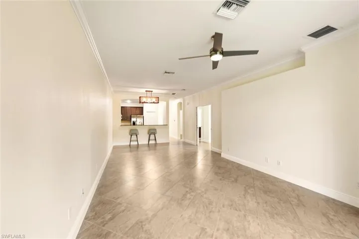 Unfurnished living room featuring ornamental molding and ceiling fan
