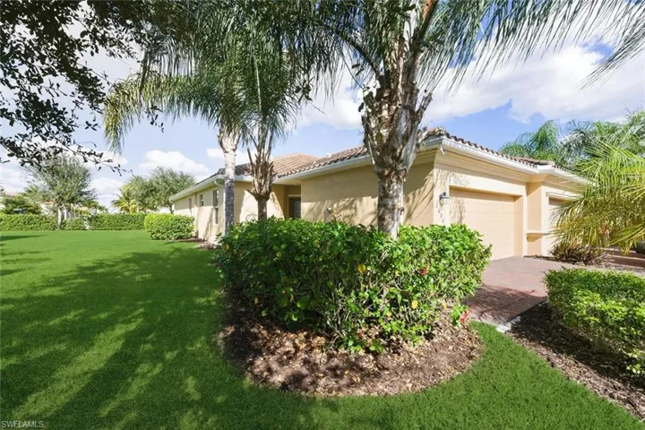 View of side of home featuring a yard, stucco siding, an attached garage, and a tile roof