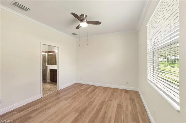 Primary Bedroom with ornamental molding, light wood finished floors, and a ceiling fan