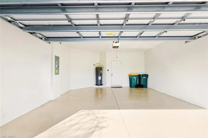 Garage featuring concrete block wall, water heater, and electric panel