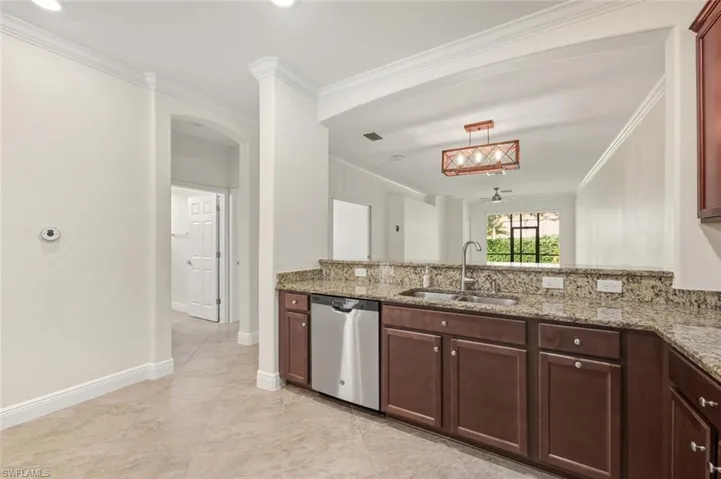 Kitchen featuring light stone countertops, stainless steel dishwasher, crown molding, a peninsula, and hanging light fixtures