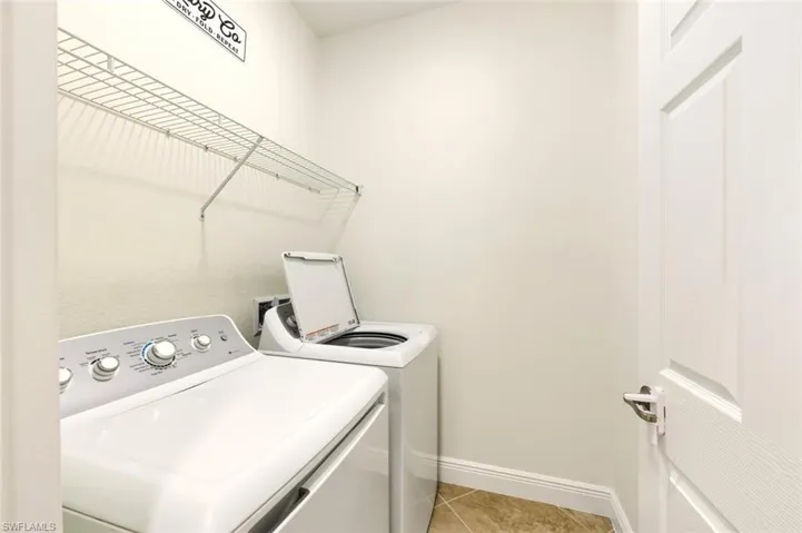 Laundry room featuring light tile patterned floors and washing machine and clothes dryer
