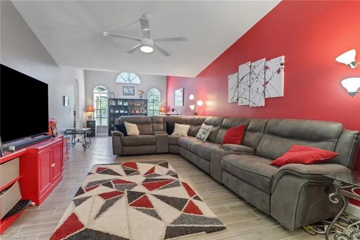 Living area with high vaulted ceiling, arched walkways, a ceiling fan, and wood finish floors