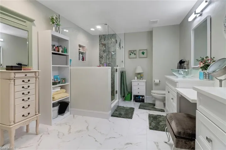 Full bath with a stall shower, marble finish floor, vanity, and toilet