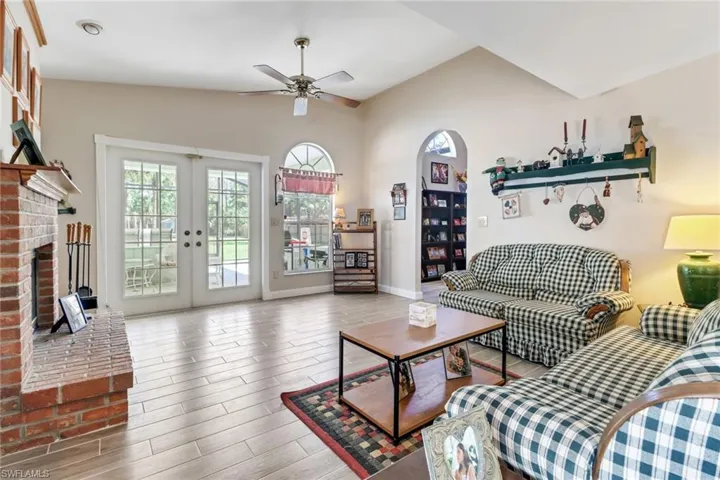Living area with french doors, a ceiling fan, vaulted ceiling, wood finished floors, and baseboards