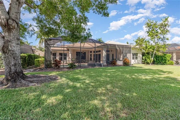 Rear view of house with a lanai, a sunroom, a lawn, and a swimming pool