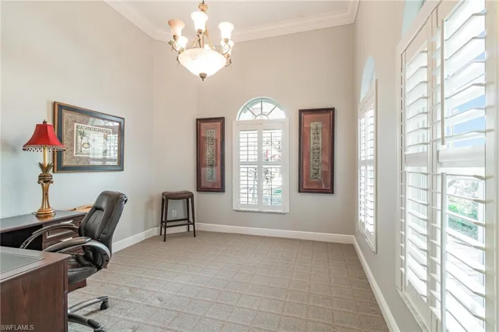 Office space with crown molding, a chandelier, and light colored carpet