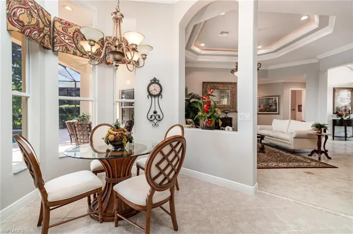 Tiled dining area featuring a tray ceiling, crown molding, a chandelier, and recessed lighting